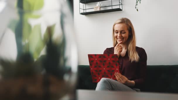 Beautiful blonde caucasian young woman looking at her colorful tablet and smiling while watching comedy show on the internet. — ストック動画