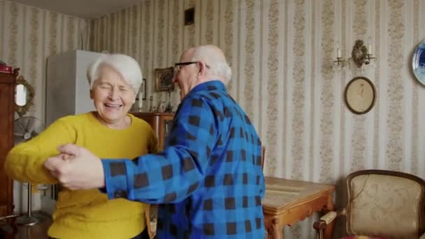 Feliz casal de idosos desfrutando enquanto dança na sala de estar, momento romântico juntos — Vídeo de Stock
