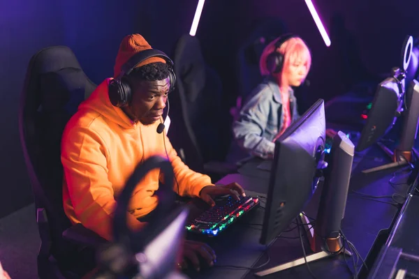 Team of professional esport gamers with happy African man in focus playing in video games on cyber games tournament indoors —  Fotos de Stock