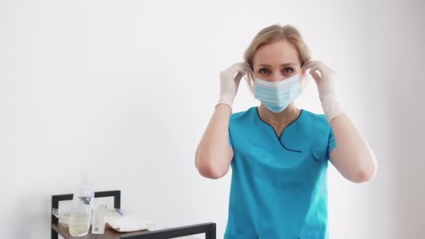 Blond sjuksköterska justera medicinsk mask medium skott vit bakgrund sjukhus vård koncept — Stockvideo