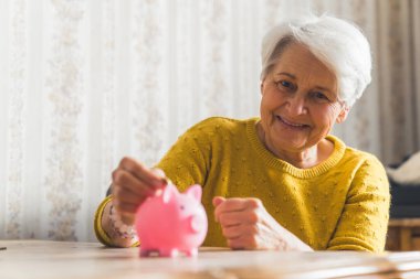 Geleceğe yatırım yapmak - güzel bir son sınıf kadını Piggy Bank 'ın orta ölçekli kapanış odası tasarruf konseptine para koyuyor