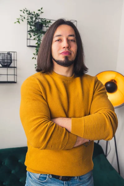 Medium shot of confident young man crossing his hands and looking at the camera casual clothes home background — Stockfoto