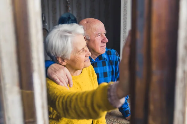 European retired senior heterosexual couple looking peacefully out of the window and thinking about their future. Tranquil retirement concept. — Stockfoto