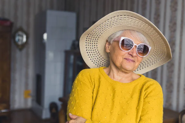 Відчувається, як літо. мила старша жінка в капелюсі і сонцезахисних окулярах в домашніх умовах концепція старшинства вітальні — стокове фото