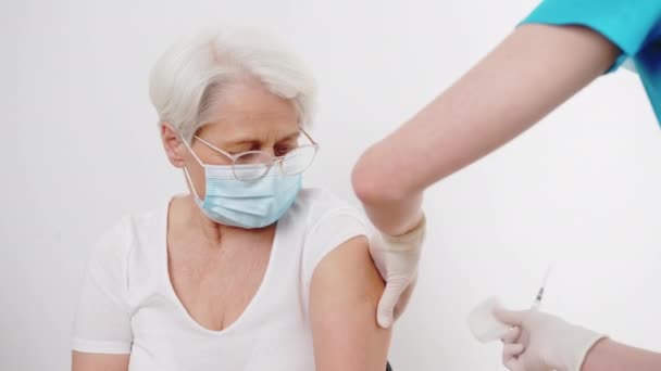 Lekarz dezynfekcja starszych kobiet ramię przed szczepieniem średnia zbliżenie biały tło wewnątrz opieki zdrowotnej koncepcja — Wideo stockowe