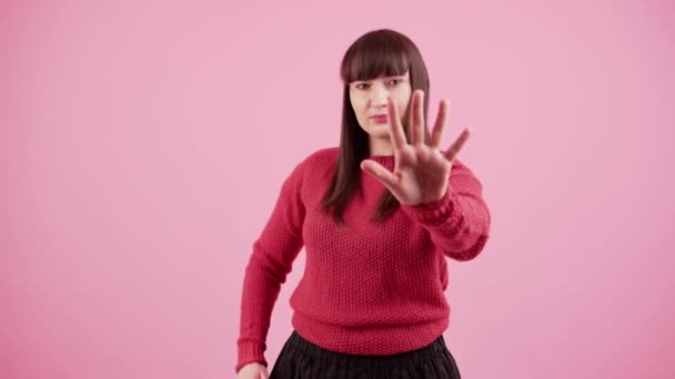 Молода брюнетка біла жінка над рожевим ізольованим фоном робить зупинку співати з долонею руки . — стокове відео