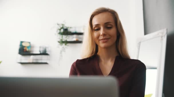 Beautiful young businesswoman in modern shirt using laptopat home — ストック動画