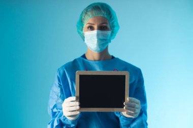 female doctor holding a blank blackboard medium closeup blue background indoor medical concept