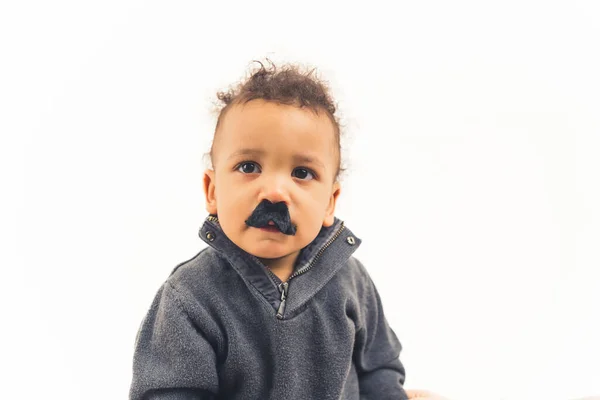 Toddler with fake black mustache looks at the camera — Photo