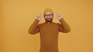 Genç, neşeli bir adam orta ölçekli çekim stüdyosunu işaret ediyor. 