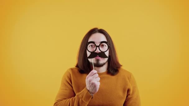 Divertido slow mo de hombre guapo con bigote falso en el fondo de color — Vídeos de Stock