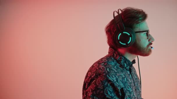 Perfil retrato de un joven barbudo con auriculares espacio de trabajo copia rosa fondo medio primer plano trabajo concepto — Vídeos de Stock