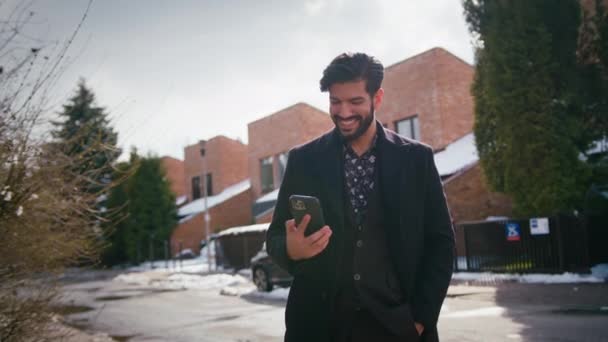 Fora tiro de um jovem empresário cubano barbudo sexy olhando para o seu smartphone, e sorrindo, desfrutando de seu trabalho. — Vídeo de Stock
