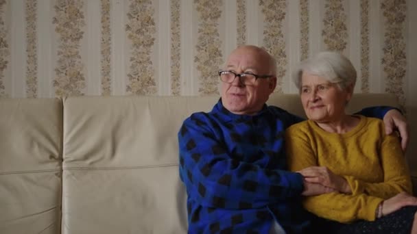 Senior happy couple enjoying time together while sitting on the couch and looking at the window, horizontal slowmotion — Wideo stockowe