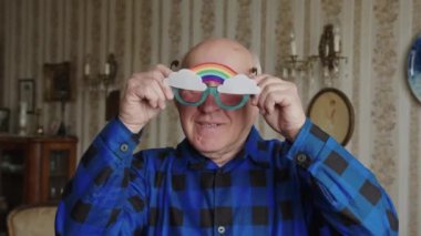 Senior European man wearing unusual rainbow glasses and laughing 