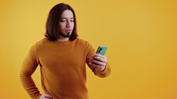 Jovem falando usando smartphone enquanto fala por um videocall, estúdio tiro — Vídeo de Stock