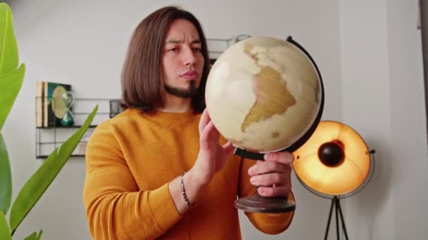 Joven alegre girando un globo geográfico y sonriendo en la oficina — Vídeo de stock