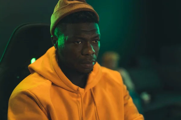Focused Black Gamer Guy Playing Computer Games And Trying To Win Another Match. Orange yellow hoodie and hat. — Fotografia de Stock