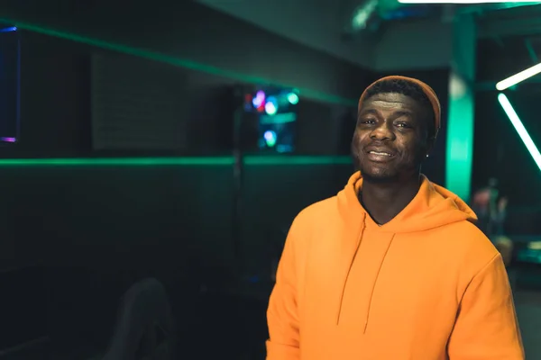 Handsome bearded African-American male gamer in an orange hoodie after a tournament in an Internet cafe. — Fotografia de Stock