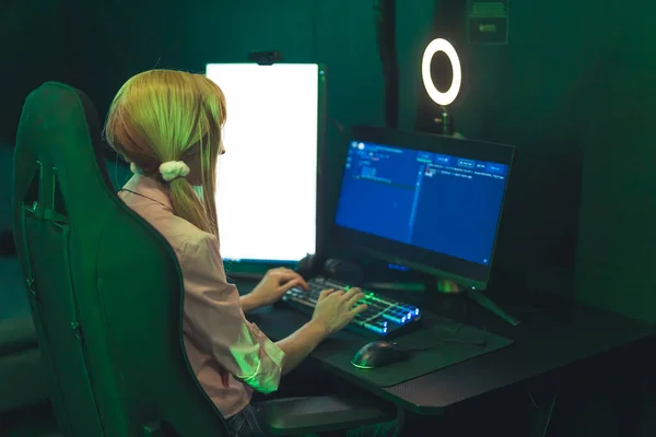 Jonge Kaukasische blonde gamer meisje met behulp van kleurrijke verlichte toetsenbord met behulp van haar professionele desktop computer. Modern technologieconcept. — Stockfoto