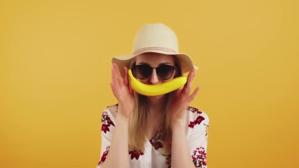 Joven mujer sosteniendo un plátano como un bigote medio primer plano estudio disparo fondo naranja — Vídeo de stock