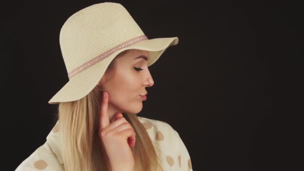 Portrait profile of a young blonde woman with a hat thinking and looking down black background closeup studio shot copy space — ストック動画