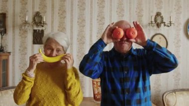 Ellerinde muz ve portakal, sahte gülümseme ve gözler olan olgun, evli bir çift. 