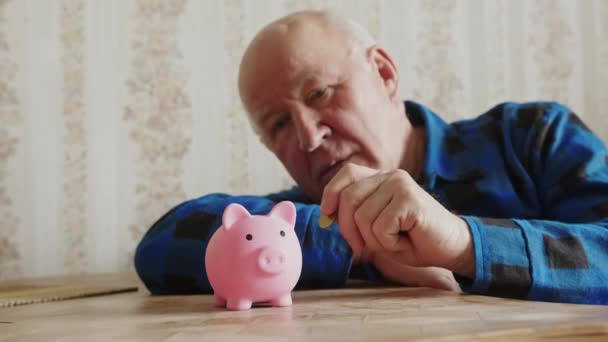 Старший кавказский человек вкладывает деньги в сберегательную концепцию свиньи — стоковое видео