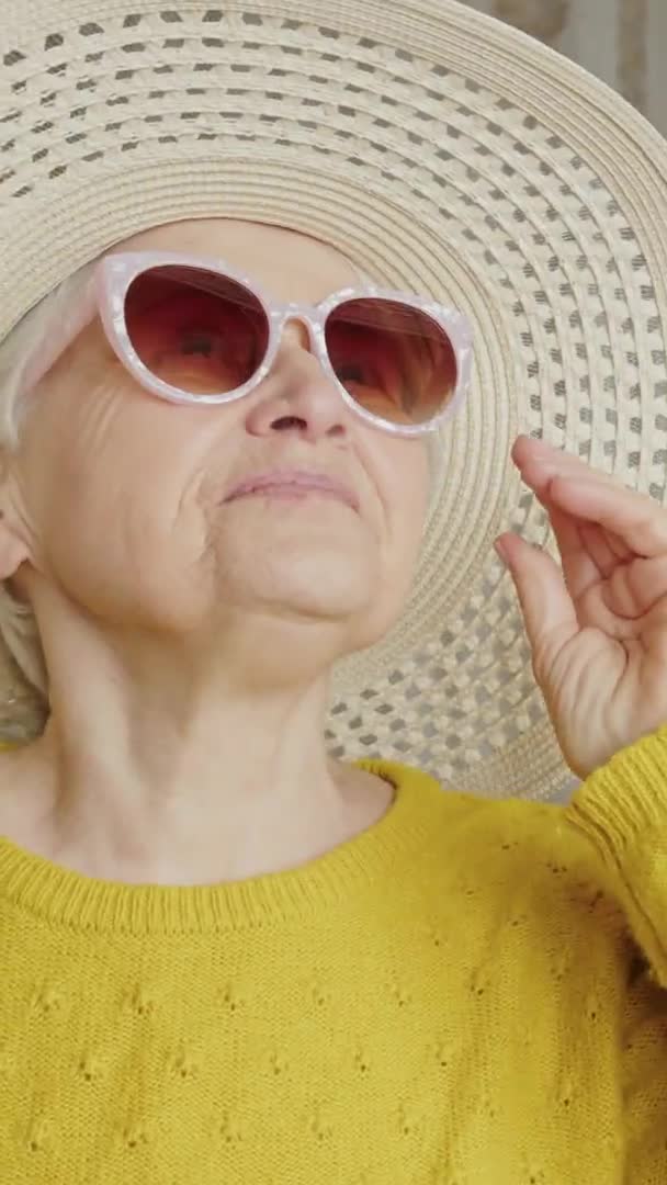 Middle aged European woman wearing hat looks up and takes off sunglasses vertical video — Video