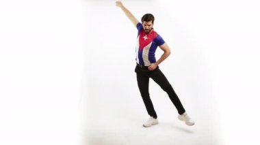 Beyaz arka planda stüdyoda dans eden kendine güvenen yakışıklı adam Küba bayraklı tişört giyiyor. Latin dansı.