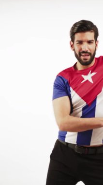 Beyaz arkaplanda dans eden, kendine güvenen yakışıklı bir adamın dikey çekimi. Üzerinde Küba bayrağı olan bir tişört vardı. Latin dansı.
