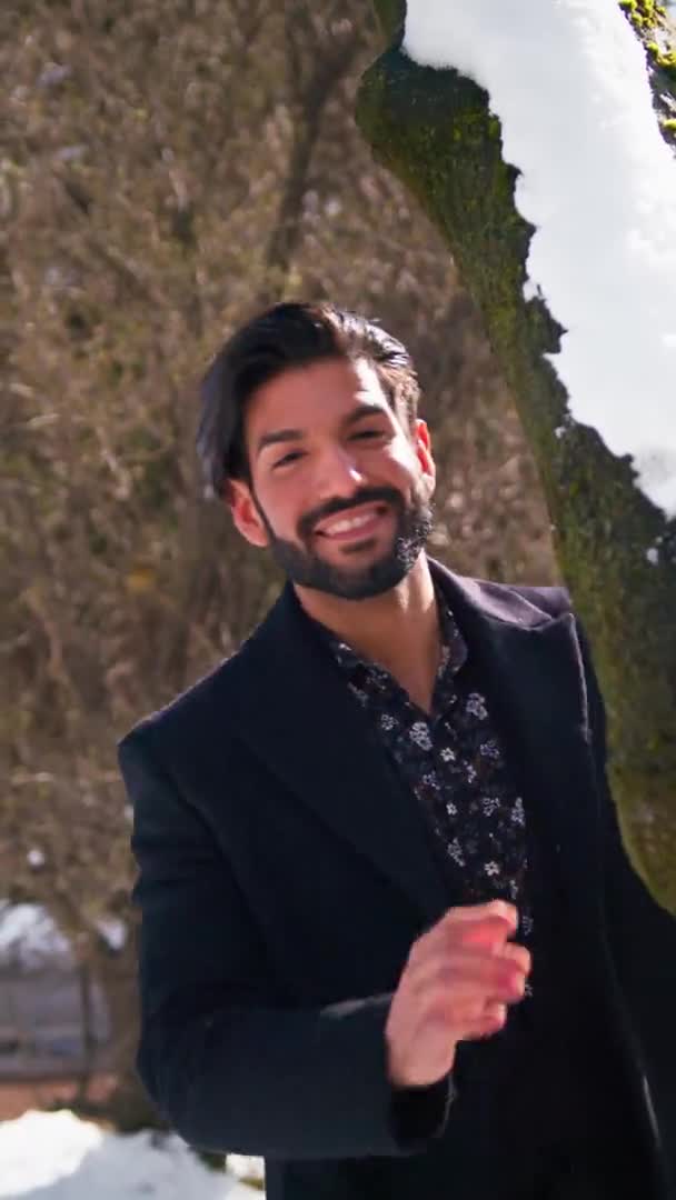 Sexy pohledný kubánský podnikatel po třicítce se dívá zpoza stromu, hraje si se sněhem a usmívá se do kamery.. — Stock video