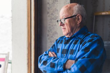 Pencere kenarından bakan kıdemli bir adam. Orta sınıf kapanış odası kıdemi.