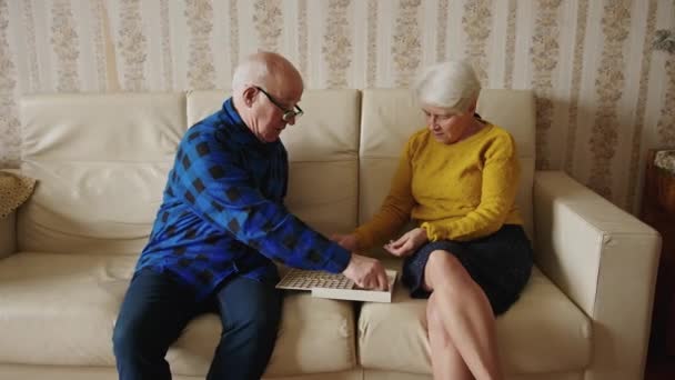 Půvabný starší pár hraje slovní zásobu hry na pohovce starší lidé podporují koncept místnosti pozadí střední plný výstřel — Stock video