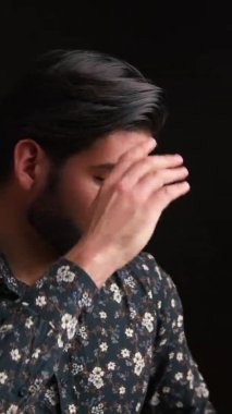 Dikey çekim stüdyosunda, siyah arka plan üzerinden parlak siyah saçlarına dokunan çekici, çekici Kübalı bir adam görülüyor. Saç ticareti konsepti.