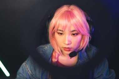  Çekici odaklı kulaklıklı Asyalı bayan hippi ve pembe peruklu video oyunları konsepti konsepti.