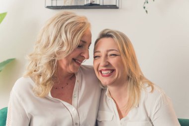 Happy mature mother and grown-up adult daughter smiling together, portrait