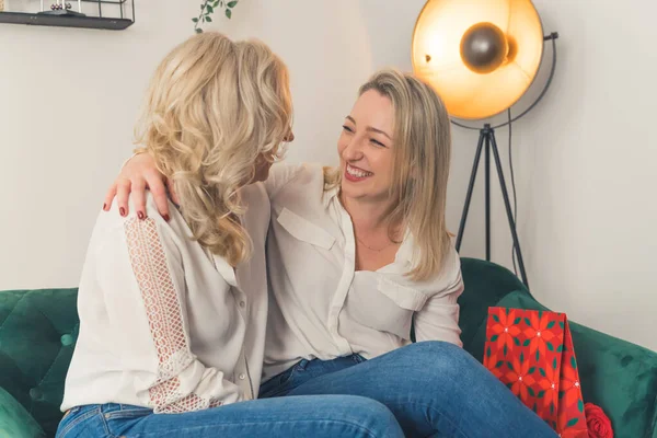 Mutlu yetişkin anne ve yetişkin kız kucaklaşır yakın samimi bir anı paylaşır, gülümser yaşlı anne ve milenyum kızı kucaklaşır