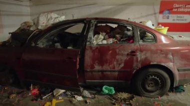 Park yerinde çöp dolu kırmızı bir araba parçalanmış.