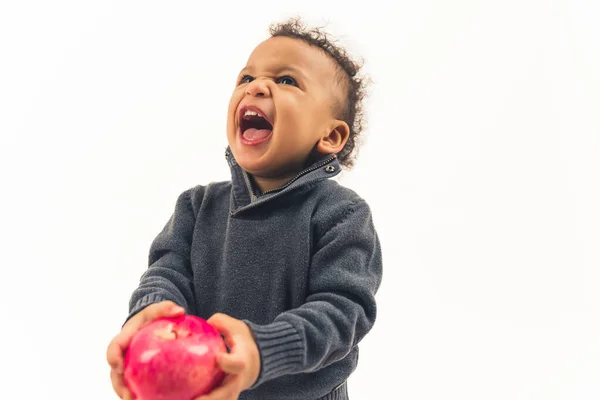 Bébé garçon multiracial mignon refusant de manger sa pomme rouge juteuse et criant sur fond blanc. — Photo
