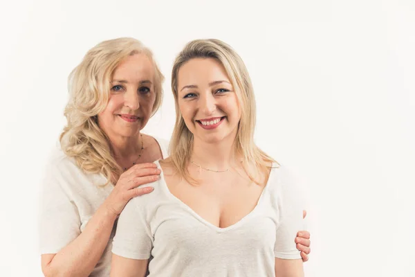 2 beautiful blonde women. Shot of a attractive mom and her young daughter over white background in the studio — Stockfoto