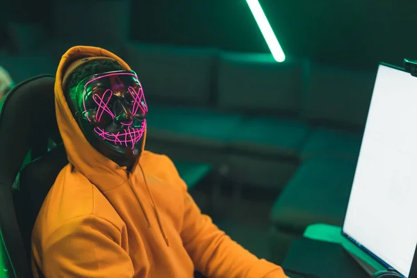 Hacker hombre con una máscara de neón de miedo medio primer plano en el interior concepto hacker —  Fotos de Stock