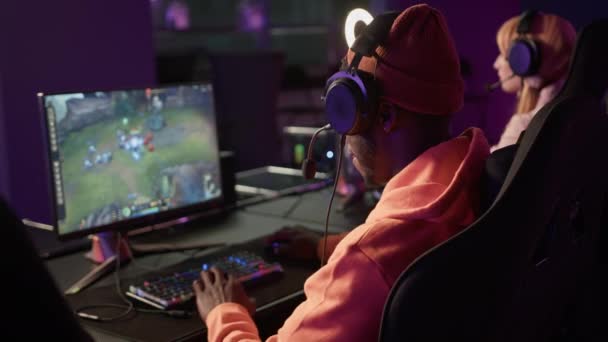 African american bearded casually dressed man wearing headset playing a popular online team game, doing a fist bump with another player. — Stock videók