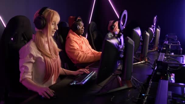 一群年轻的多种族快乐玩家坐在职业游戏室的游戏椅子上，赢得了一场在线比赛 — 图库视频影像