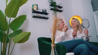 blonde Caucasian women doing make up in living room medium full shot indoors feminine concept