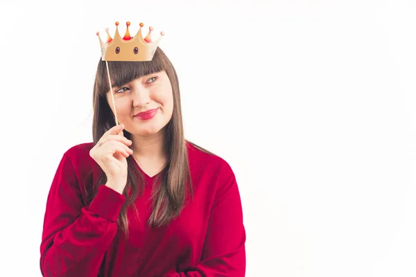 Portrait pretty young woman looks away holding paper crown above her head isolated studio shot white background copy space — Stock fotografie