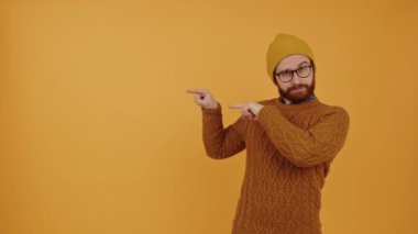 young bearded Caucasian man pointing left orange background medium shot studio shot advertisement concept