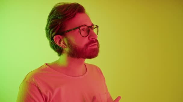 Jonge bebaarde Europese man met bril met een telefoontje via airpods medium close-up gele achtergrond studio shot job concept — Stockvideo