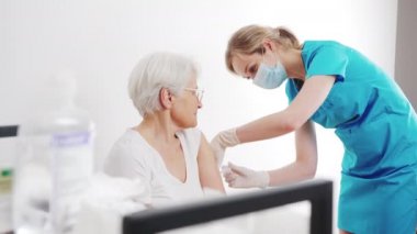 Genç ve çekici sarışın Kafkas hemşire yaşlı kadın hastaya aşı yapıyor orta boy hastane sağlık sigortası konsepti.