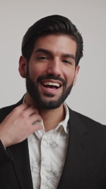 Acımasız bir adam elbisesinin üzerindeki gömleği düzeltir. Gülümser geniş, şık, erkek giyim tarzı, dikey.